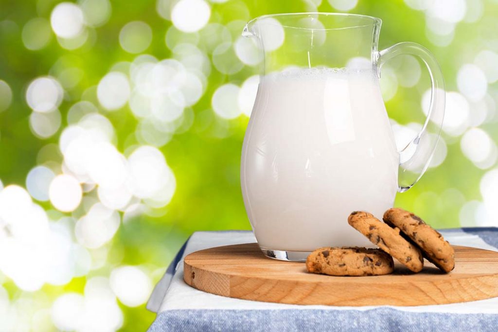 Jarra de leche con galletas de chocolate sobre una tabla de madera